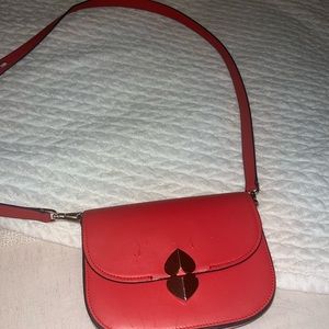 small kate spade cross body bag. cherry red color with heart detail buckle